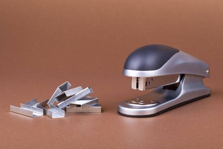 Feed the stapler - office stapler and staples on brown backgroundの写真素材