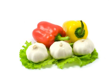 Garlic on green leaf and red and yellow paprika on the white backgroundの写真素材