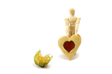 Wooden man standing with heart and with physalisの写真素材