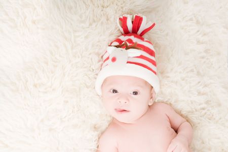 Newborn baby in chritstmas hat lies on furの写真素材
