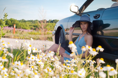 Beautiful brunette woman sitting near car
