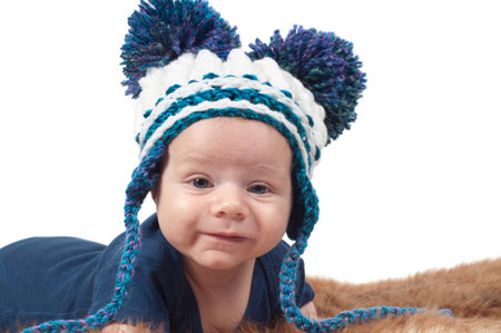Cute baby in knitted hat with big pom-pons