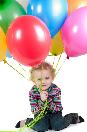 Little girl with multicolored air balloons sitting on the floorの写真素材