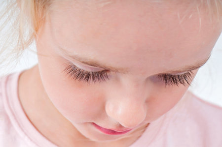 Close-up portrait of beautiful blonde little girl with long eyelashes