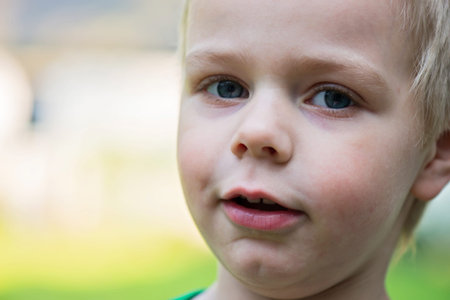 Outdoor closeup portrait of happy kid face. Shallow depth of field. Focus on the left eye