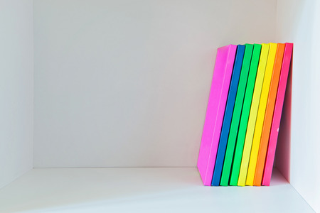 Multi colored books on the light-coloured bookshelf with copy-spaceの写真素材