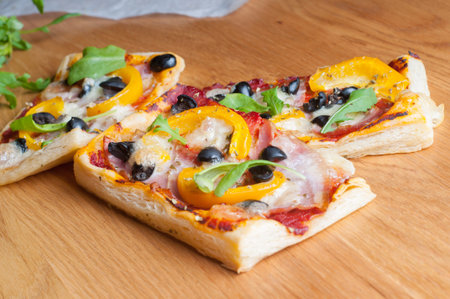 Puff pastry cakes with rucola and olives on the wooden tableの写真素材