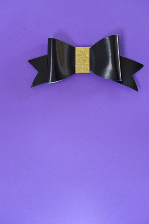 Black and golden bow tie over ultra violet background.の写真素材