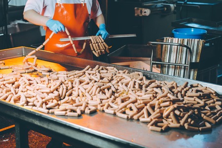 butcher processing sausages at meat factoryの写真素材
