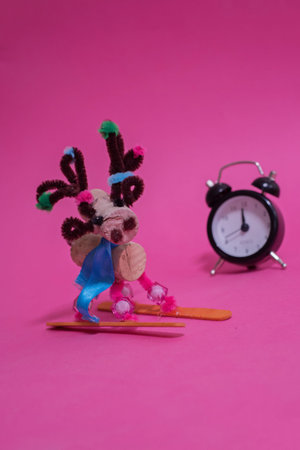 Handmade christmas elk over pink background with clock