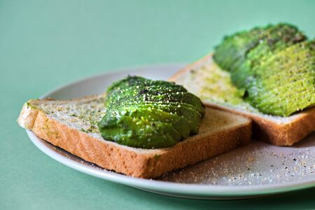 Avocado on toast on the plate over mint backgroundの写真素材