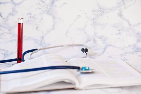 Stethoscope, book and blood analysis Tablet in the fingers of handの写真素材