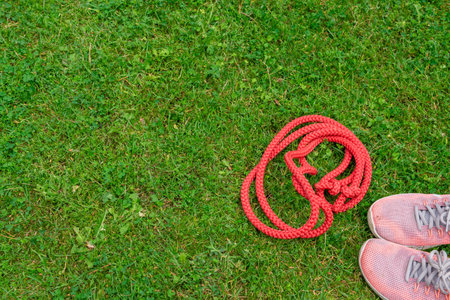 Skipping rope and sneakers on the green grass background