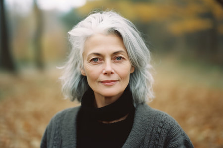Smiling middle age grey-haired woman on the beach. Autumnの素材