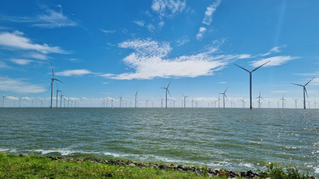 Windmills overlooking large body of waterの写真素材