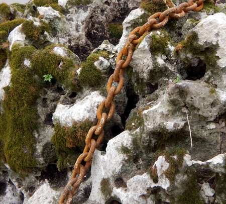 Old sea stone with moss and rusty chainの写真素材
