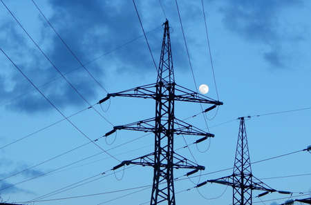 Full moon over pylons of high voltage power lineの写真素材