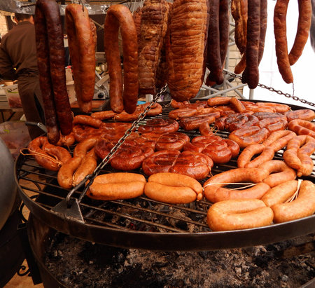 Smoked meat and grilled sausages on giant grill