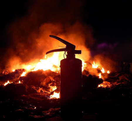 Fire extinguisher over burning fire at night closeupの写真素材