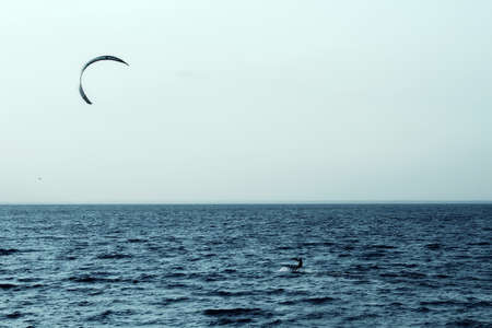 Kite surfer rides on the waves in sea bay at sunsetの写真素材