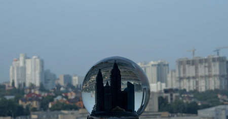 Toy town in snow globe against the backdrop of real city buildingsの写真素材