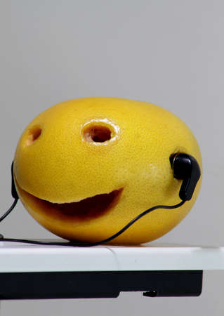 Musical metaphor. Smiling orange in earphone studio isolatedの写真素材