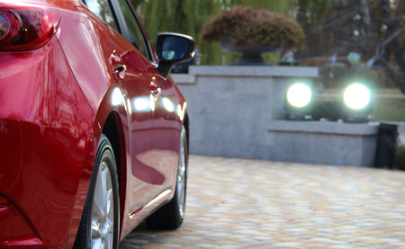 Red vehicle in ray of spotlight on the paving stones at the private parking