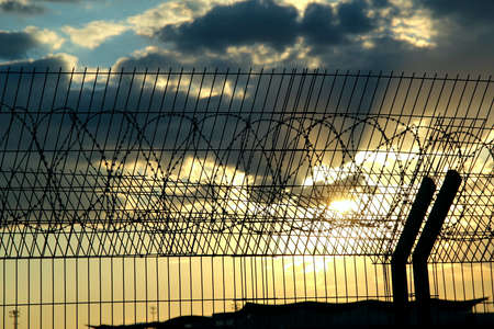 Airport safety fence over cloudy sky stock photoの写真素材