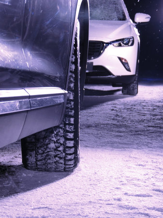 Black car against white car on the snow road at nightの写真素材