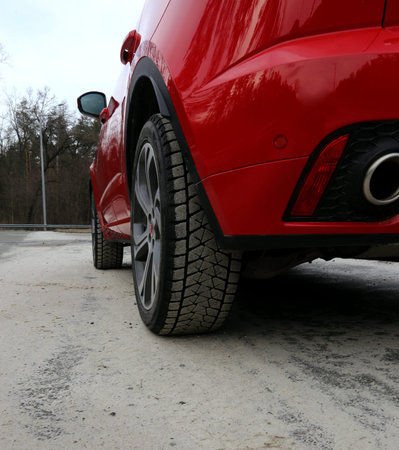 Red car on the road with tires packed with sand at spring time
