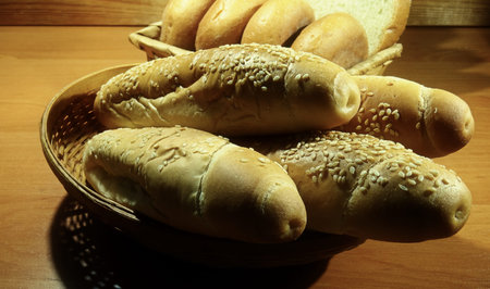 Fresh rolls, sesame buns and wheat bread on the wooden shelf at bakery shop
