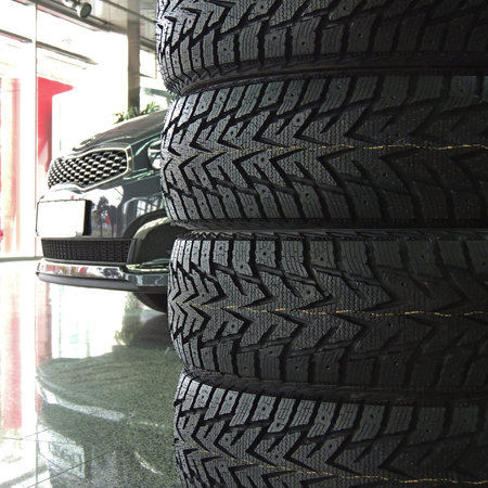 Stacked tires in front of the car in dealership showroomの写真素材