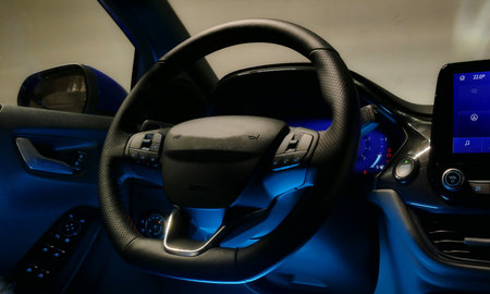 Steering Wheel With Control Buttons In Car Interior With Blue Backlight