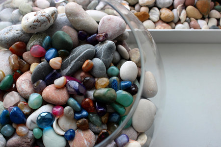 Round glass sphere filled with semi-precious stones next to a box of sea pebbles and shellsの写真素材