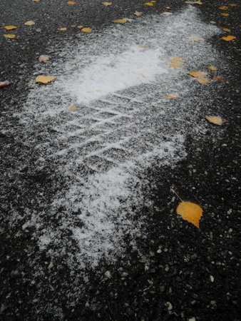Dangerous road condition concept photo. Ð car drove through a snowy area on ice with frozen leaves vertical stock photoの写真素材