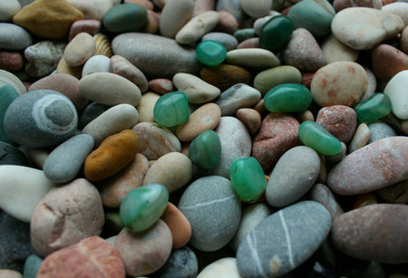 Raw smooth aventurine stones on round pebbles mixed with small sea shells