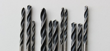 Black metal drills on white plastic sheet in a shape of barcode