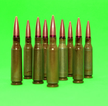 Cartridges for gun weapon with red lines on a bullets with sharpen and soft focus isolated on green...