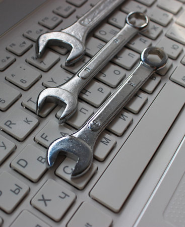 Metallic wrenches on a buttons of laptop keyboard vertical stock photo. Different types of hardware...