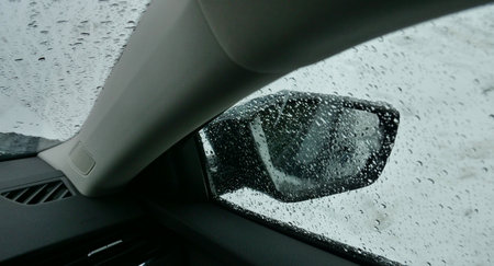 View from inside of a car on a drop pattern on the glass and snow on the side mirror. Car heater melting snow from car glasses after snowfallの写真素材