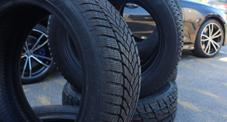 Car is visible through the new tires staying on the edge. Stacked tires set ready to be mounting on a carの写真素材