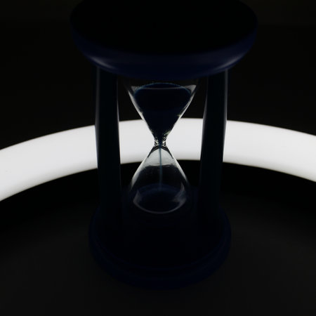 Illuminated Trickle Of Sand Inside Hourglass In Darkness Closeup Viewの写真素材