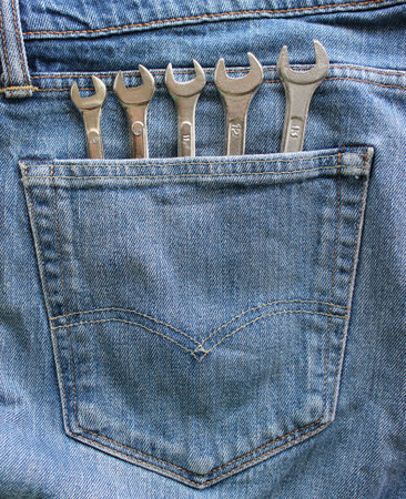 Steel wrenches arranged by size sticking out from the denim pocket. Vertical stock photo for home...