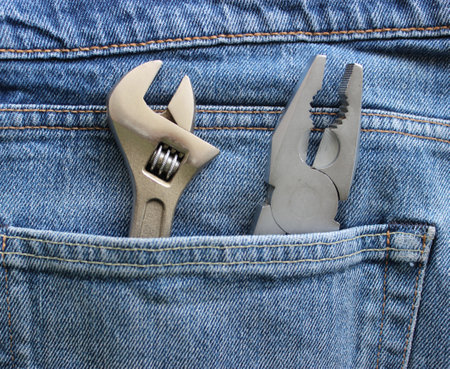 An adjustable spanner and pliers are placed in a jeans pocket. Closeup stock image for home repair themeの写真素材