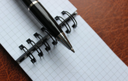 Business Pen On A Binder Of Checkered Note On A Leather Folderの写真素材