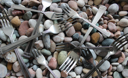 Heap Of Cake Forks And Table Forks On A Colored Sea Stones Closeup Viewの写真素材