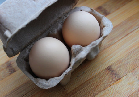 Breakfast For Two Concept Stock Photo. Original paper tray for two eggs on wooden planks surfaceの写真素材