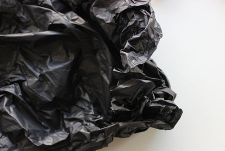 Crushed Wadded Up Sheet Of Black Polyethylene On White Background. Stock Photo For Plastic Recyclingの写真素材