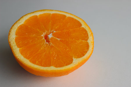 Ripe orange cut in half on a white surface at the side of the image. Stock photo for fruits backgroundsの写真素材