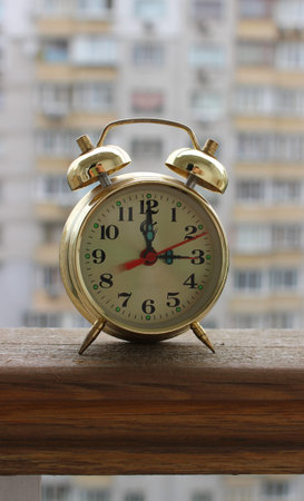 Classic copper clock with bells on a background of blurred residential apartments